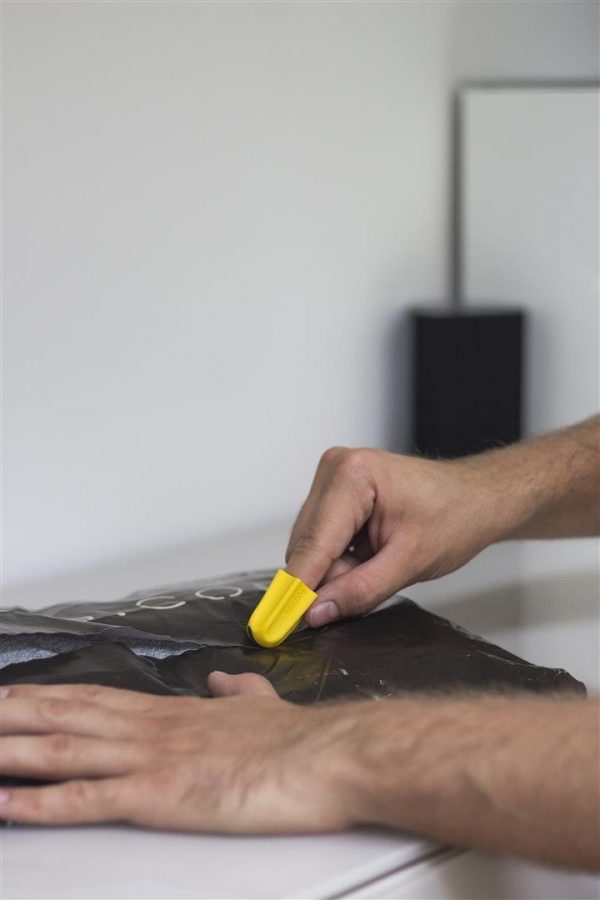 Nimble one-finger cutter opening a black plastic bag