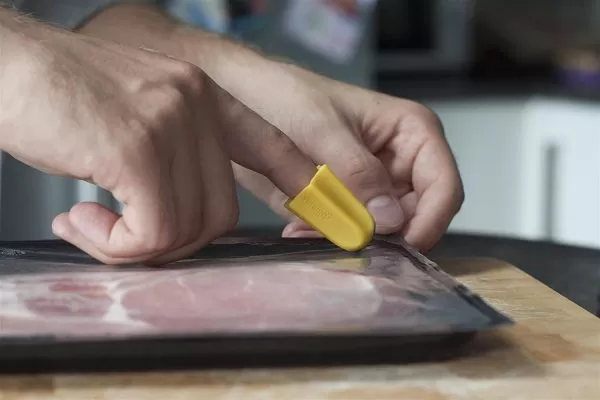 Nimble one-finger cutter opening a pack of ham