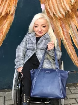 Sam Renke holding her accessible wheelchair handbag in navy