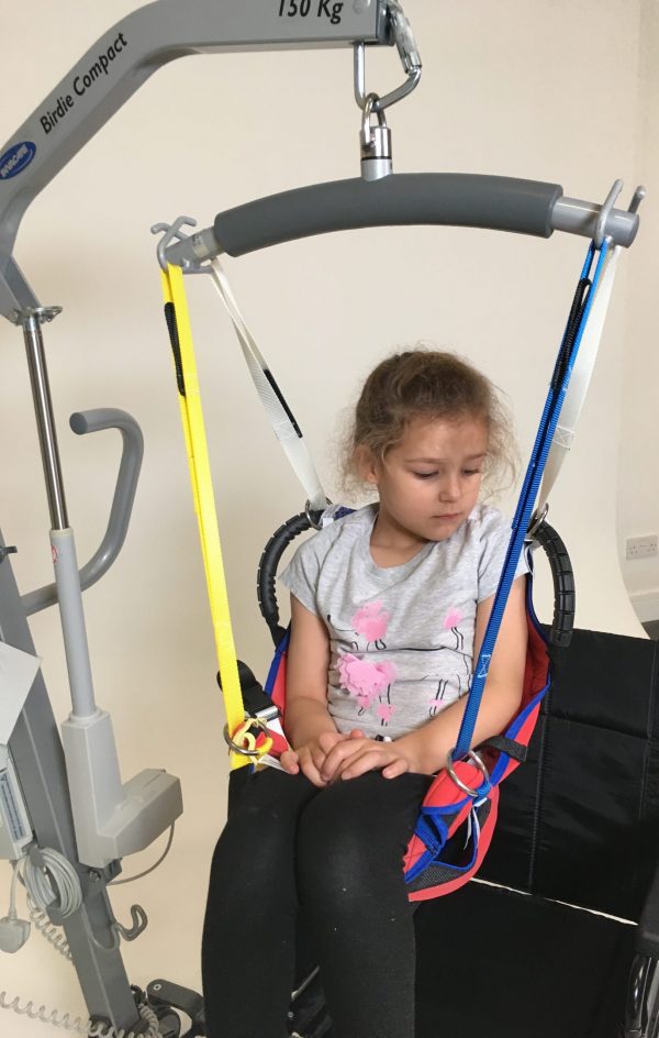 Young disabled girl being moved in ProMove sling with straps attached to the hoist