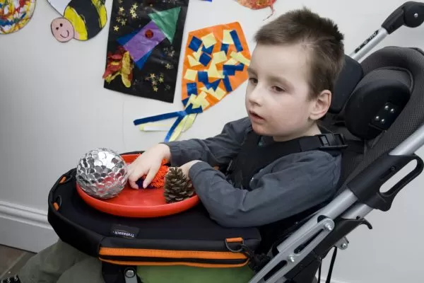 Trabasack Curve Connect wheelchair lap tray and bag on a disabled child's lap with a toy on top