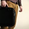 Trabasack Mini wheelchair lap tray and bag being carried with the short handles