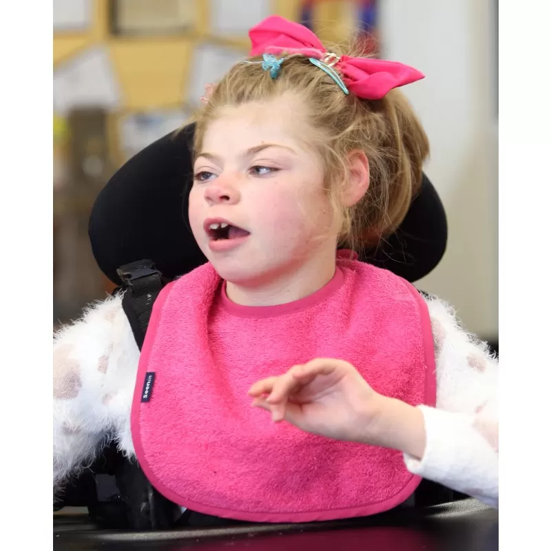 Disabled girl wearing Seenin bib in pink