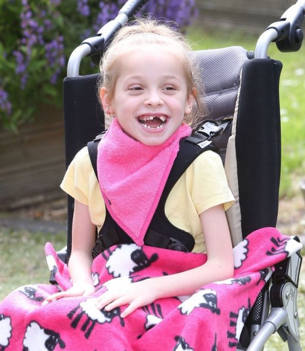 Girl in a wheelchair wearing Seenin kerchief bib in pink