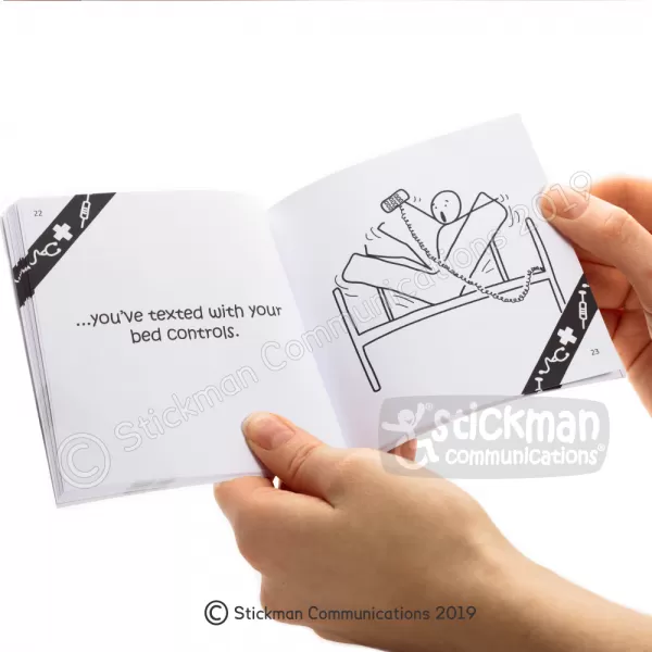 Image is a photograph of a hand holding open the "You Know You've Been in Hospital..." book to show the content inside