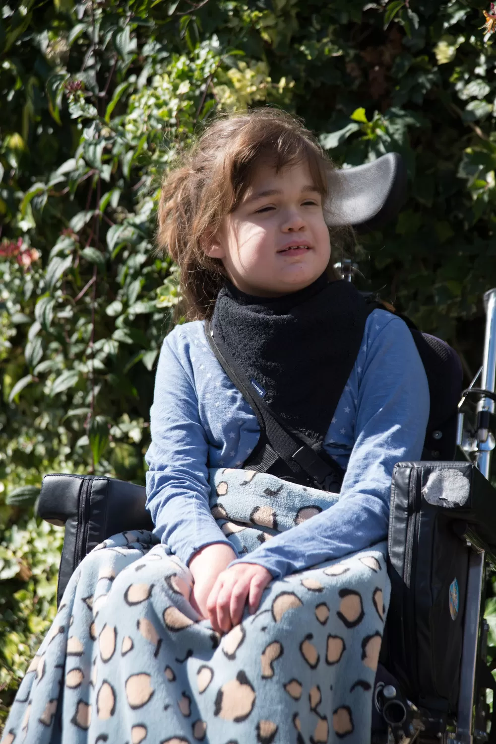 Disabled girl wearing Seenin fleece wheelchair leg cover in blue leopard print