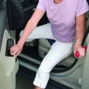 A lady uses a handy bar to get out of the car