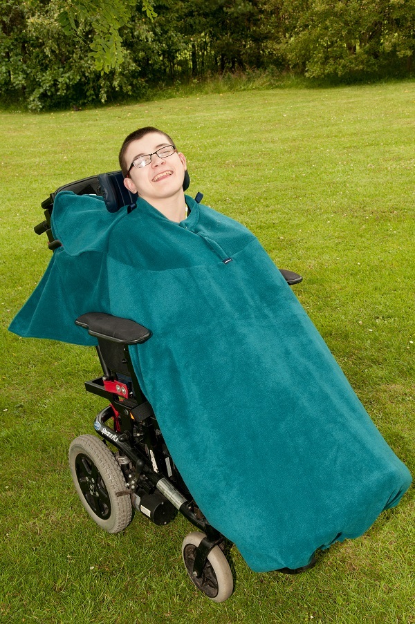 Disabled man in field wearing teal Seenin total fleece wheelchair cover