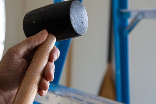 Image is a photograph of someone holding a hammer with Cat Tongue Grip Tape on the handle