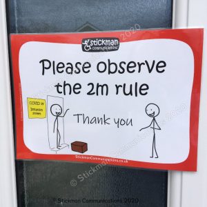 Image is a photograph of a poster attached to a door. On the poster a stickman waves and smiles from his front door, with a package at his feet, whilst another stickman smiles and is seen to be keeping 2 meters in distance away. Text reads: "Please observe the 2m rule - thank you"