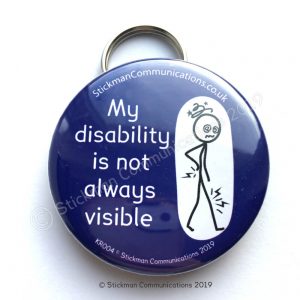 Image is a photograph of a blue, circular keyring with an illustration of a stickman with a dizzy head and aching joints. Text reads: "My disability is not always visible"