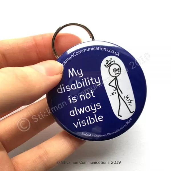 Image is a photograph of a hand holding a blue, circular keyring with an illustration of a stickman with a dizzy head and aching joints. Text reads: "My disability is not always visible"
