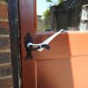 Image is a photograph of the exterior of a backdoor with a black, metal level handle with a Tru Grip handle extender attached