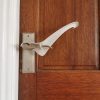 Image is a photograph of a wooden, varnished door with a brushed steel level handle, with a Tru Grip door handle extender attached