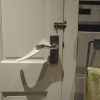 Image is a photograph of a white internal house door with a Try Grip handle extension kit installed upside down to aid those with arthritis