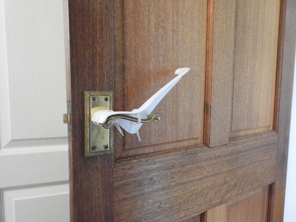 Image is a photograph of a brass internal door handle with a Tru Grip door handle extension kit installed