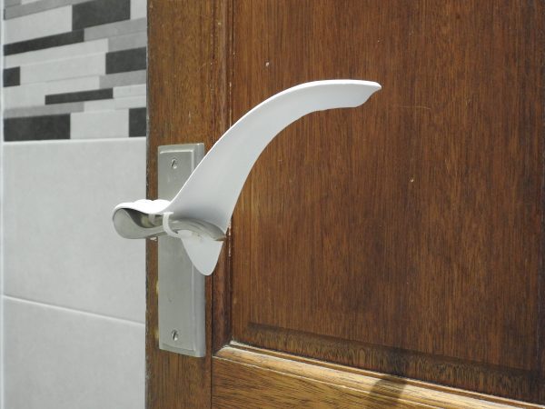 Image shows an internal wooden house door with the plastic Tru Grip door handle extender installed