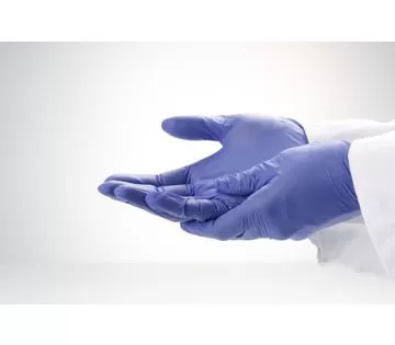Image is a photograph of two hands wearing cornflower blue nitrile gloves for sensitive hands. Both hands are facing upwards, with one placed atop the other.