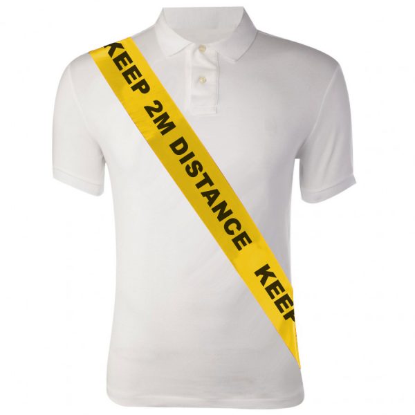 Image is a photograph of a mannequin torso wearing a white polo shirt, with a yellow silky sash worn from the shoulder, around the chest and to the waist. Black, capitalised text on the sash reads "KEEP 2M DISTANCE"