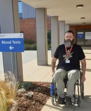 Zec in his wheelchair wearing the face mask exemption card heading into a hospital