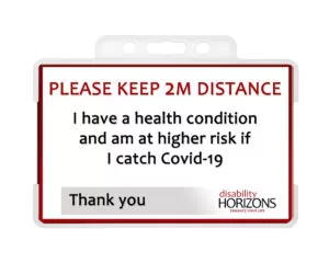 Image is a plastic ID card to promote social distancing, in a plastic ID card holder. Bright red text in capitals reads: "PLEASE KEEP 2M DISTANCE". Under this black text reads: "I have a health condition and am at higher risk if I catch Covid-19. Thank you". The bottom righthand corner features the Disability Horizons logo.