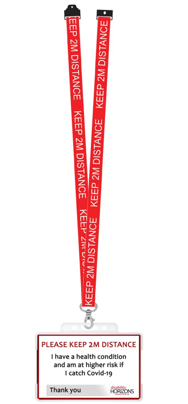 Image is a plastic ID card to promote social distancing, in a transparent plastic ID card holder and red lanyard, with white text in capitals that reads “KEEP 2M DISTANCE”. On the ID card bright red text in capitals reads: "PLEASE KEEP 2M DISTANCE". Under this black text reads: "I have a health condition and am at higher risk if I catch Covid-19. Thank you". The bottom righthand corner features the Disability Horizons logo.