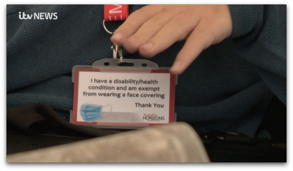 Image is a photograph of Joe Edwards' wearing the Mask Exempt ID card with text which reads: "I have a disability/health condition and am exempt from wearing a face covering. Thank you" The ID card also includes the Disability Horizons logo