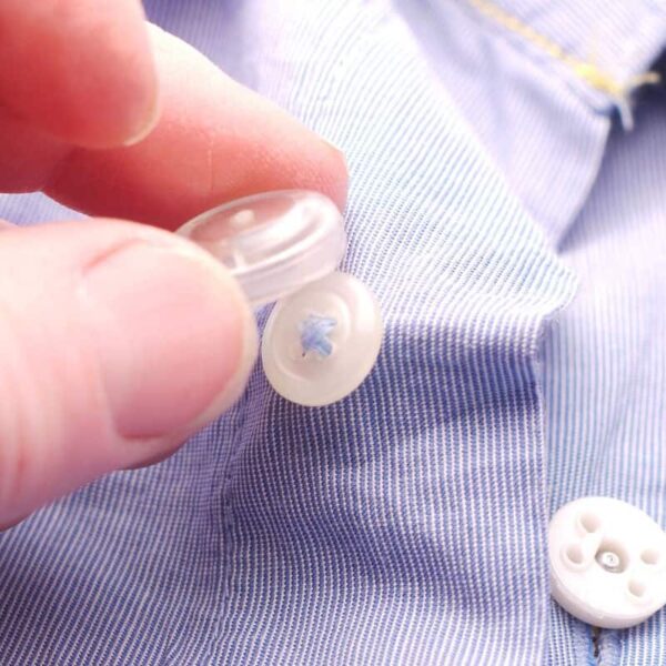 Image is a photograph of a man attaching a Buttons 2 Button magnetic button adapter to the white button on a blue shirt.