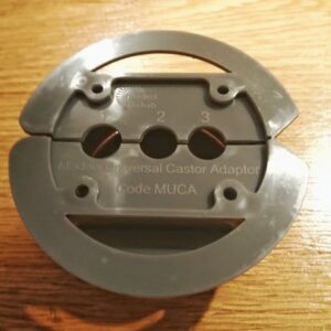 Underside of a universal castor adaptor for chair and bed raisers with a circle of plastic around the outside and three holes in the middle