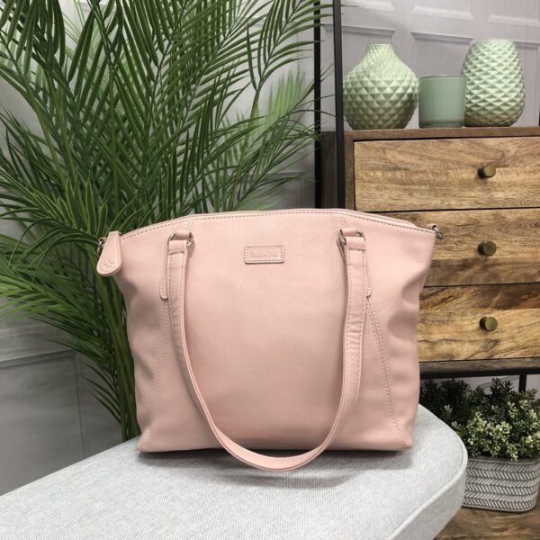 Image is a photograph of a Samantha Renke accessible handbag in Blush on a table in a living room