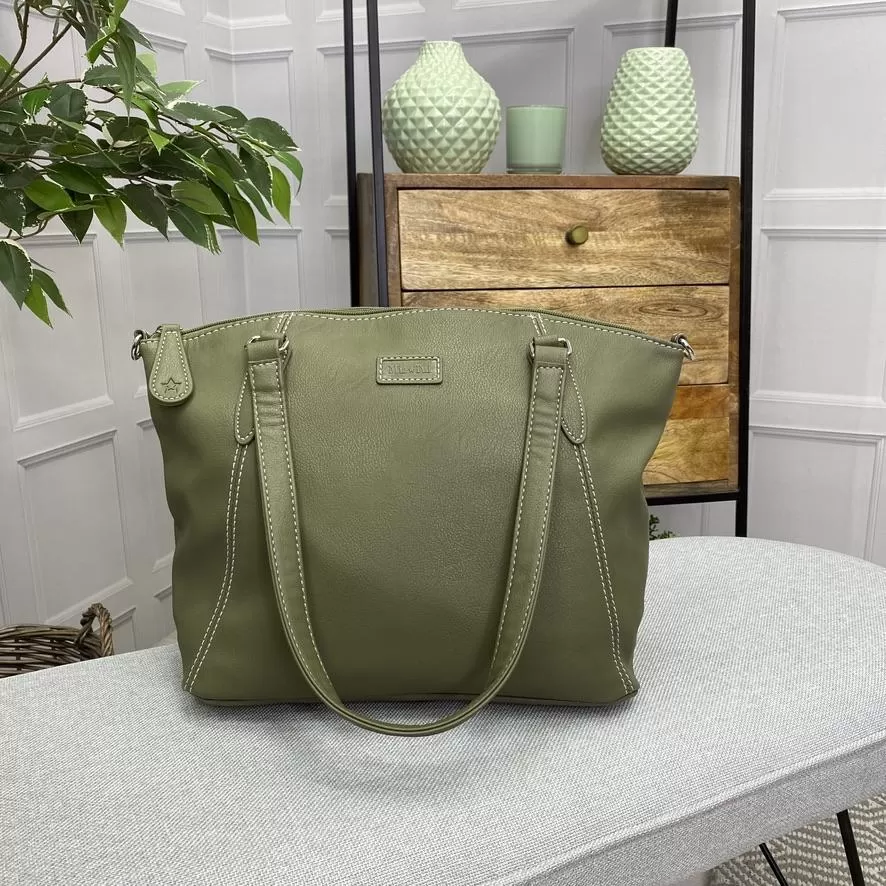 Image is a photograph of a Samantha Renke accessible handbag in Olive on a table in a living room