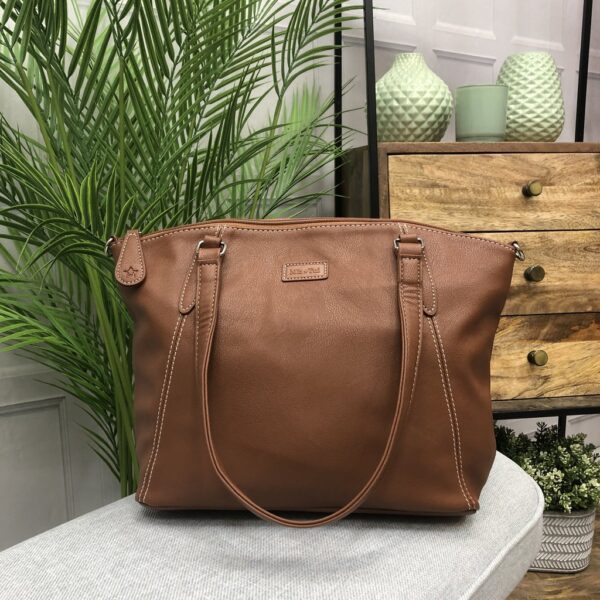 Image is a photograph of a Samantha Renke accessible handbag in Tan on a table in a living room