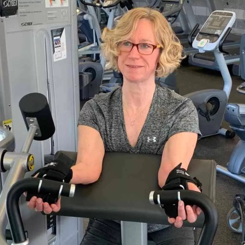 A lady using the hook aid to exercise in a gym with a rowing machine