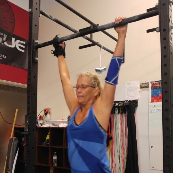 A woman using the limb difference aid to grip unto some gym bars.