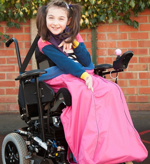 Young girl in a powerchair with a pink wheelchair fleece cover