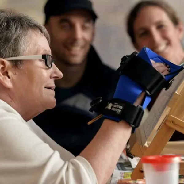 a lady using the small item gripping aid to paint a picture