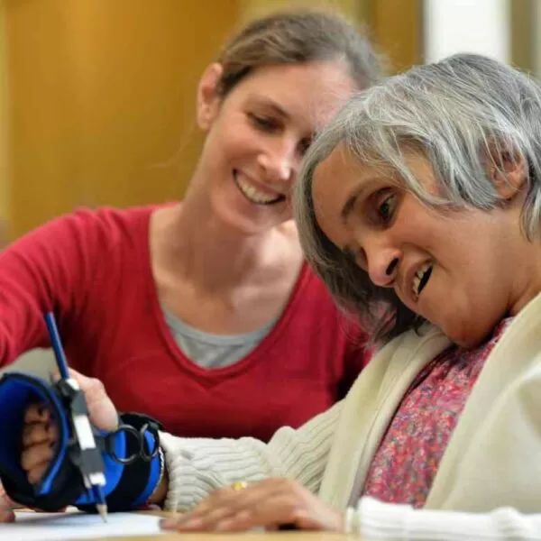 A lady using the small item gripping aid to draw a picture with a pencil