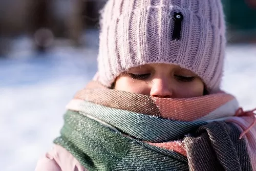 A women wearing a winter hat with a scarf covering her mouth