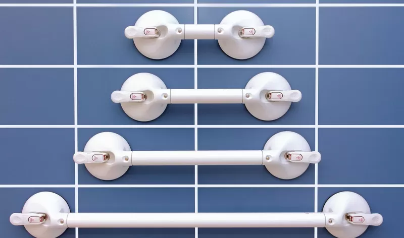 Four different sizes of Mobeli grab rails stuck onto a wall with smooth blue tiles