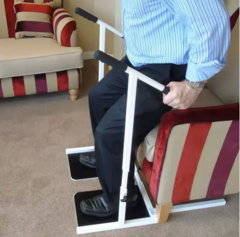 man in a blue shirt using the standing frame to stand from a chair