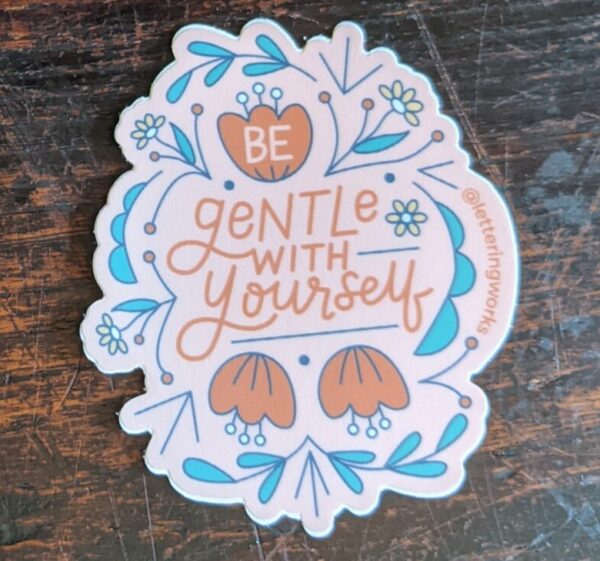 be gentle with yourself sticker on a wooden table