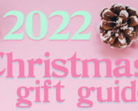 Pinecones scattered across a light pink background, with blue and pink text which reads "2022 Christmas gift guide".