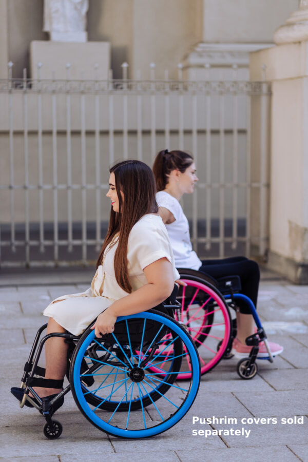 Two young women in manual chairs with reflective spokes on the wheels