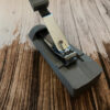 one handed nail clippers, grey base with the nail clippers set into them on a wooden table top