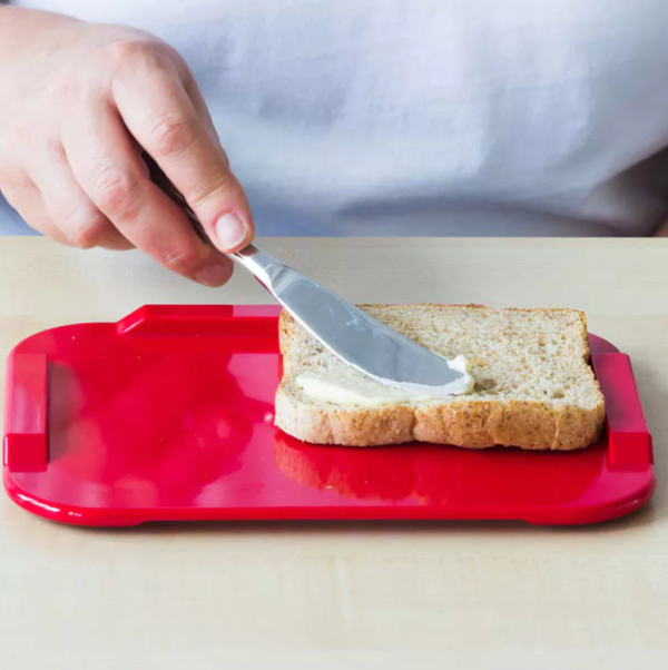 Non-slip tray being used to spread butter on toast with one hand, showing use for one handed food preparation