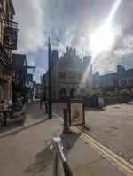 The anchor pub, Horsham, street furniture, a sign and a blue sky with the sun coming through the clouds flaring the photo