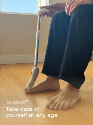 Person using a long-handled nail clipper to trim toenails while seated. Text reads: “liveSoulo. Take care of yourself at any age.”