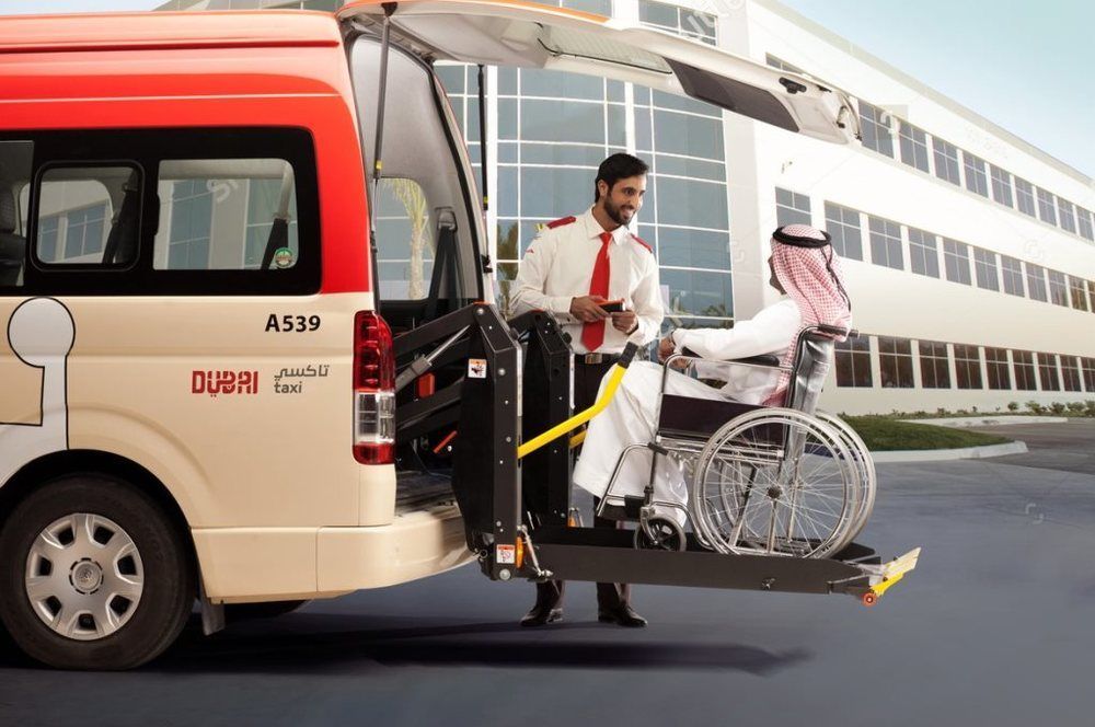 A man in traditional arab dress on a wheelchair lift going into a taxi