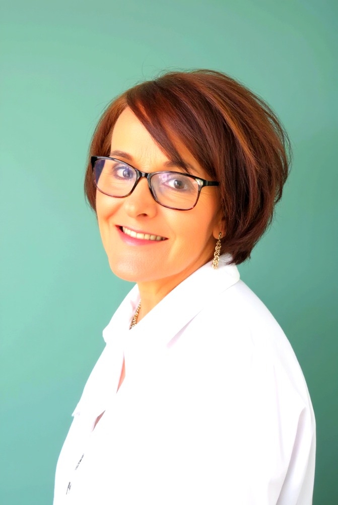 Bio image of Helen Pugh, Smiling woman with short auburn hair and glasses, wearing a white shirt against a turquoise background.